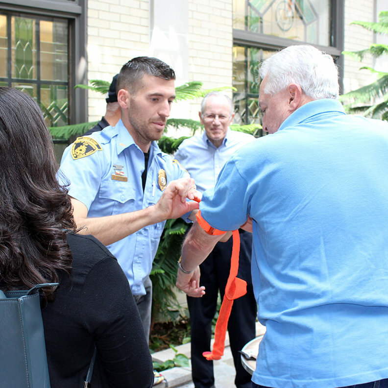 A man tying a tourniquet to an elderly man's arm in a display of medical aid.