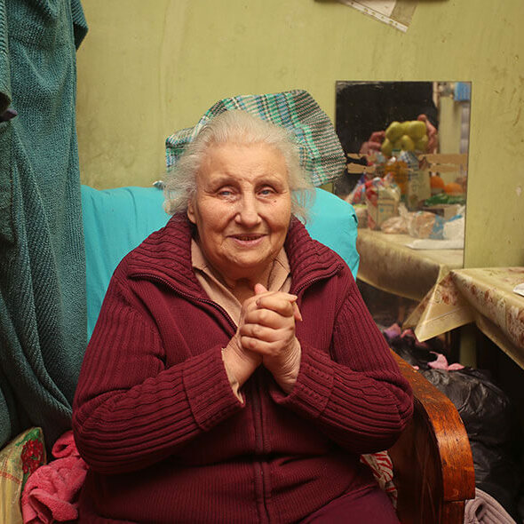 A woman sitting with her hands clasped in front of her.