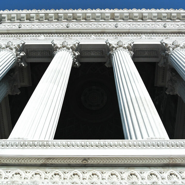 A low angle shot of a building with four white pillars.