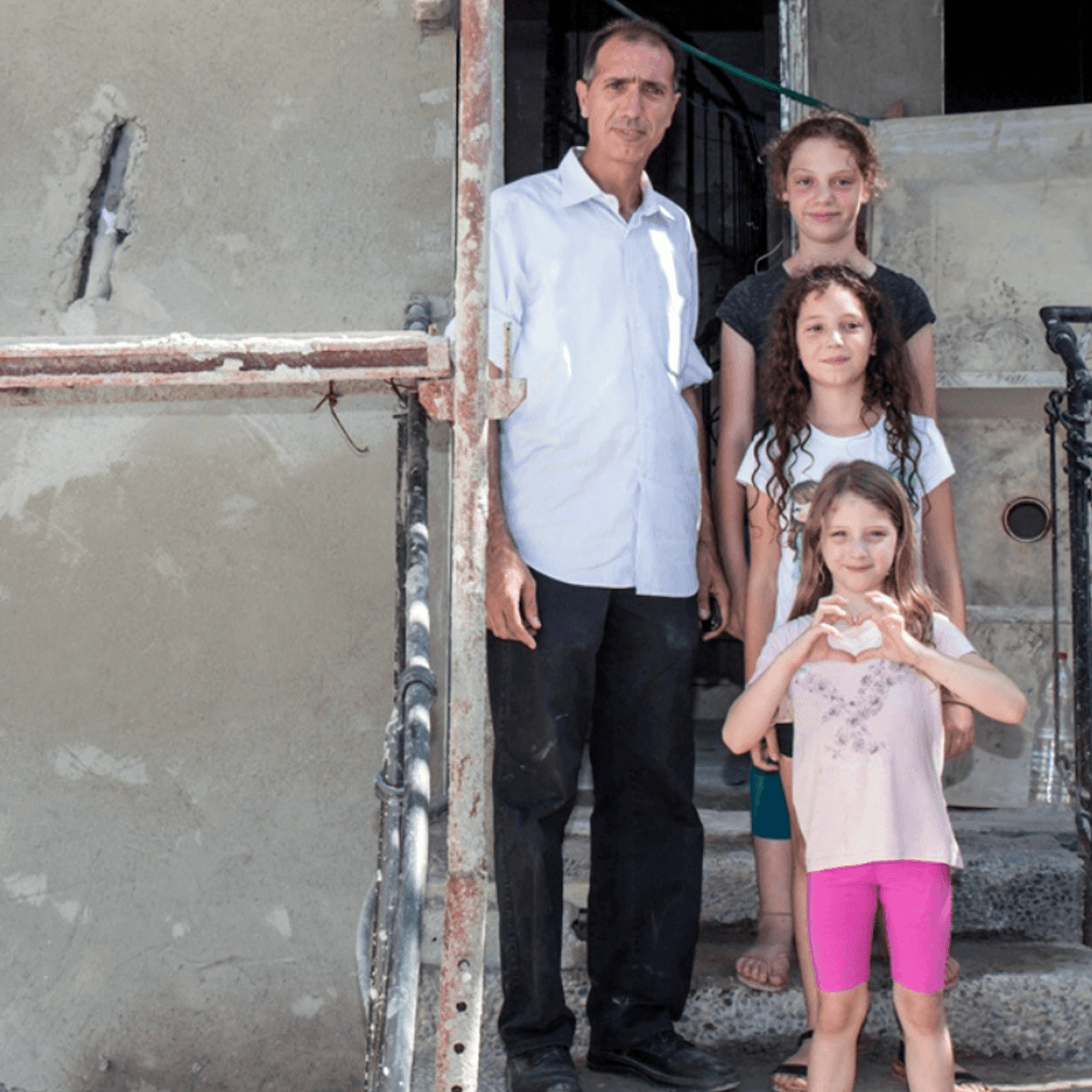 JAFI image of family in front of their damaged home