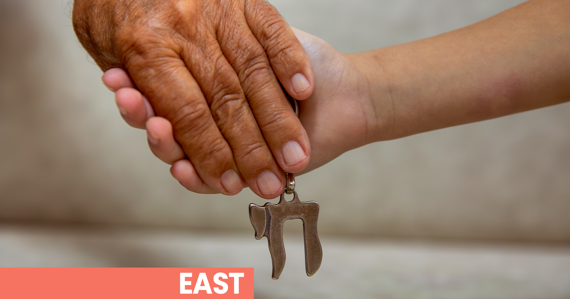 Two hands holding a Hebrew character